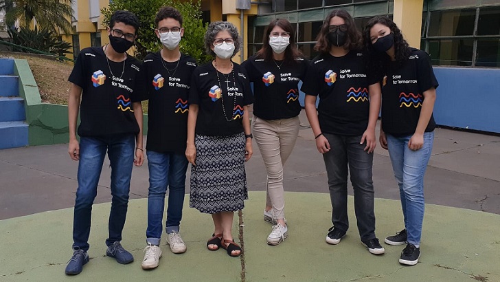 Quatro alunos e duas professoras vestidos com a camiseta do programa em pátio da escola