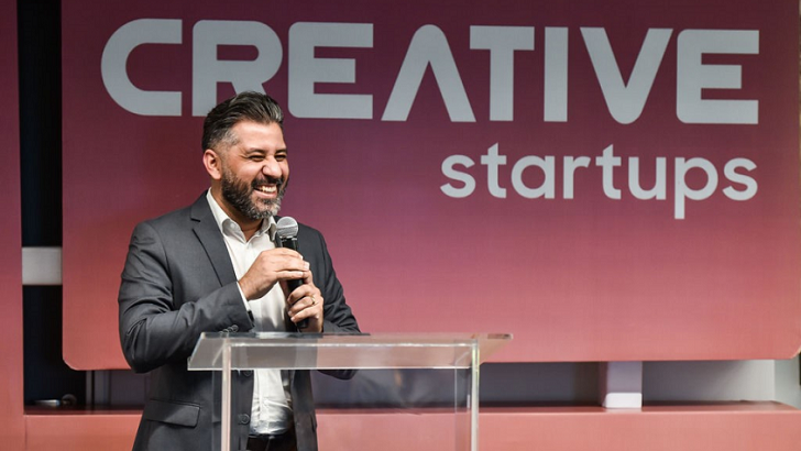 Paulo Quirino, Gerente de Inovação da Samsung, falando em frente a um painel com o logotipo do programa