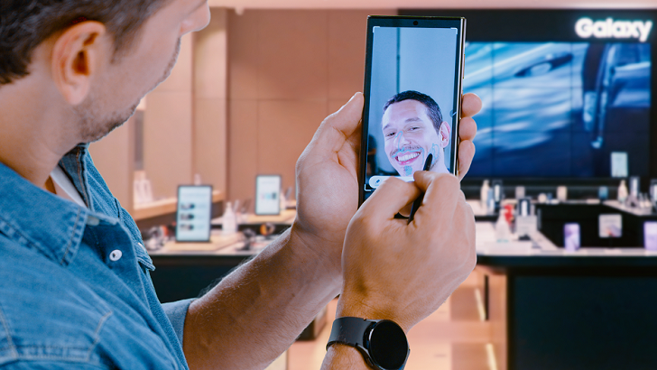 Ator João Vicente de Castro usando smartphone e smartwatch Galaxy em loja da Samsung