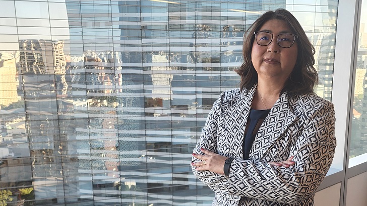 Cristina Koezuka de braços cruzados em frente para uma janela de vidro