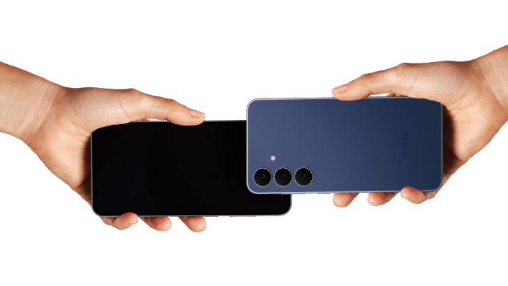 Uma imagem com fundo branco de duas mãos segurando dois smartphones um na direção do outro. O celular da direita é roxo, e o da esquerda tem a tela preta desligada.