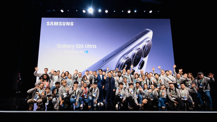 Participantes do Galaxy Unpacked 2026 posam juntos em frente à banner do novo Galaxy S26 Ultra, da Samsung