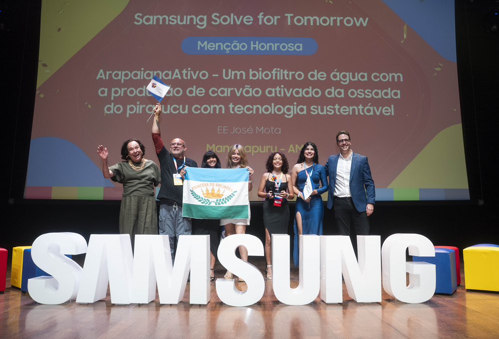 Alunas e professores posam para foto junto a representantes da Samsung em frente a letreiro da marca