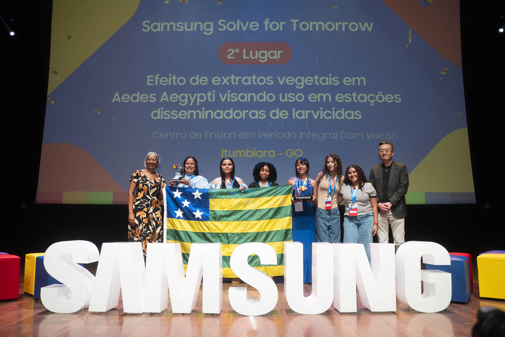 Alunas e professoras posam para foto junto a representantes da Samsung em frente a letreiro da marca