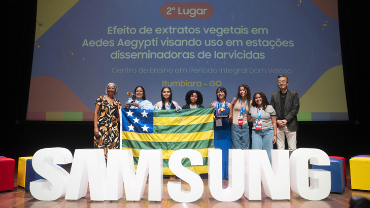 Alunas e professoras posam para foto junto a representantes da Samsung em frente a letreiro da marca