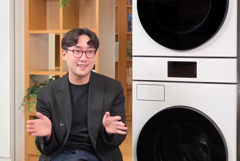 O CMF Design Group da DA Business da Samsung gesticula ao lado de um dos eletrodomésticos de lavanderia da marca