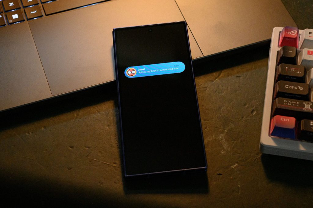 Samsung Galaxy Z Fold7 fechado exibindo um alerta do Spidey Tracker na tela externa, notificando um possível avistamento do Homem-Aranha nas proximidades por meio de uma interface em estilo pixel art.