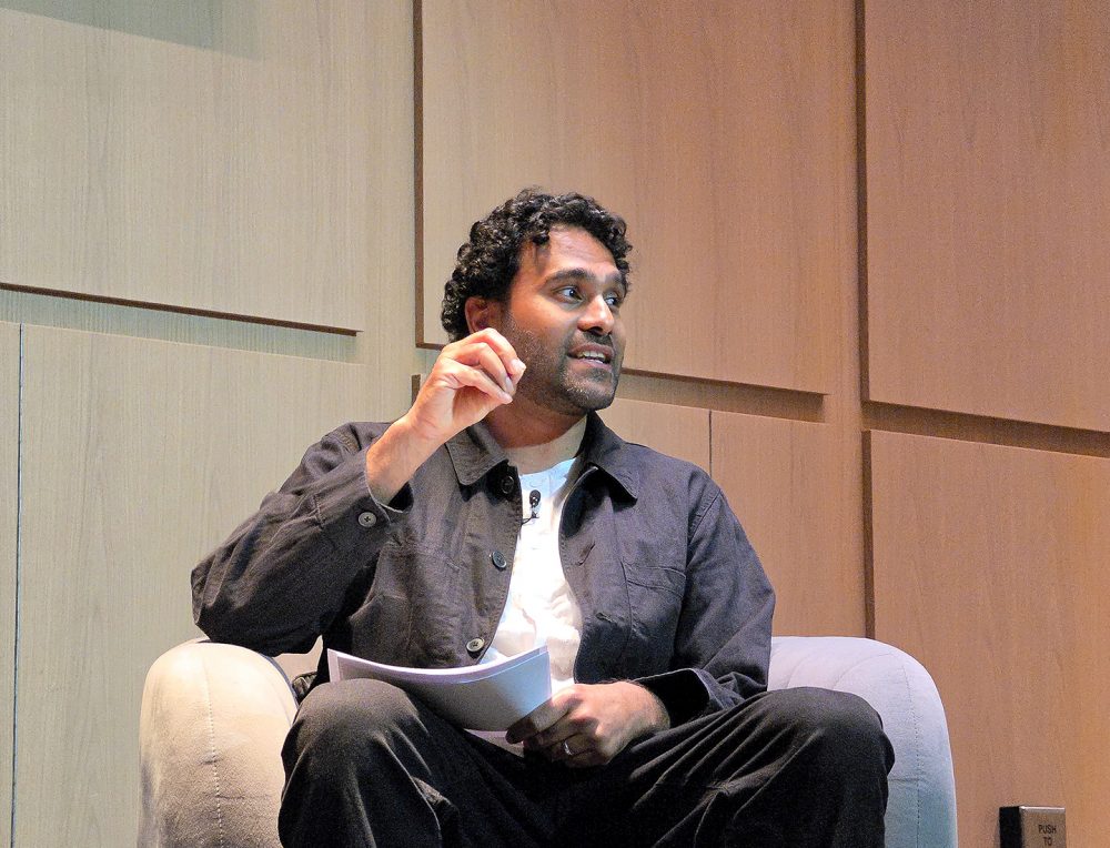 Kartik Poria, chefe de produto da Samsung Food, participa do painel sentado em uma poltrona, segurando anotações enquanto faz uma apresentação.