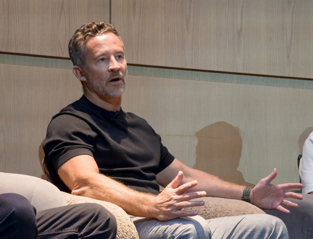 Kevin Duffy, CEO da iFIT, participa do painel sentado em uma poltrona, gesticulando com as mãos durante sua apresentação.