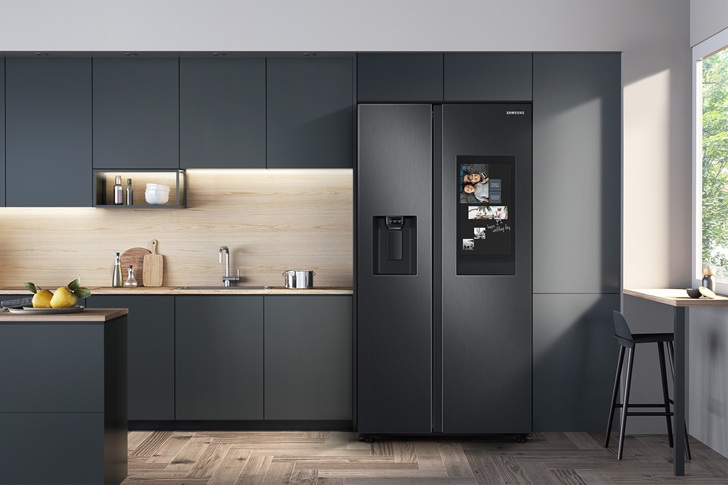 A Geladeira Side by Side RS58 é apresentada integrada a uma cozinha moderna, com acabamento em aço escovado e design minimalista que harmoniza com os armários em tons escuros. O modelo conta com dispenser externo de água e gelo e tela AI Home integrada à porta, que permite acessar informações, controlar dispositivos conectados e utilizar recursos inteligentes no dia a dia. A imagem destaca a combinação entre tecnologia, praticidade e um design sofisticado para cozinhas contemporâneas.