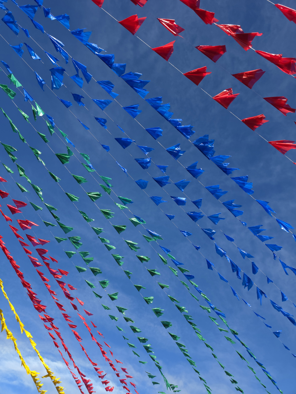 Bandeirolas vermelhas, azuis, verdes e amarelas atravessam o céu azul durante as festas de São João em Irecê, na Bahia.
