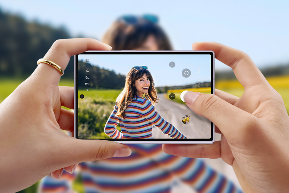 Pessoa utiliza o Galaxy Z Fold8 na horizontal para fotografar outra pessoa ao ar livre. A imagem destaca o sistema de câmeras duplas de 50 MP, desenvolvido para registrar imagens em alta resolução com lentes grande-angular e ultra-angular.