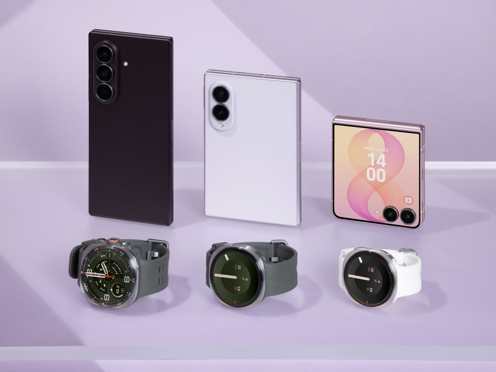 A imagem mostra os novos Samsung Galaxy Z Fold8 Ultra, Z Fold8 e Z Flip8 posicionados em pé em uma superfície lisa. À frente deles estão o Galaxy Watch Ultra2 e dois Galaxy Watch9.