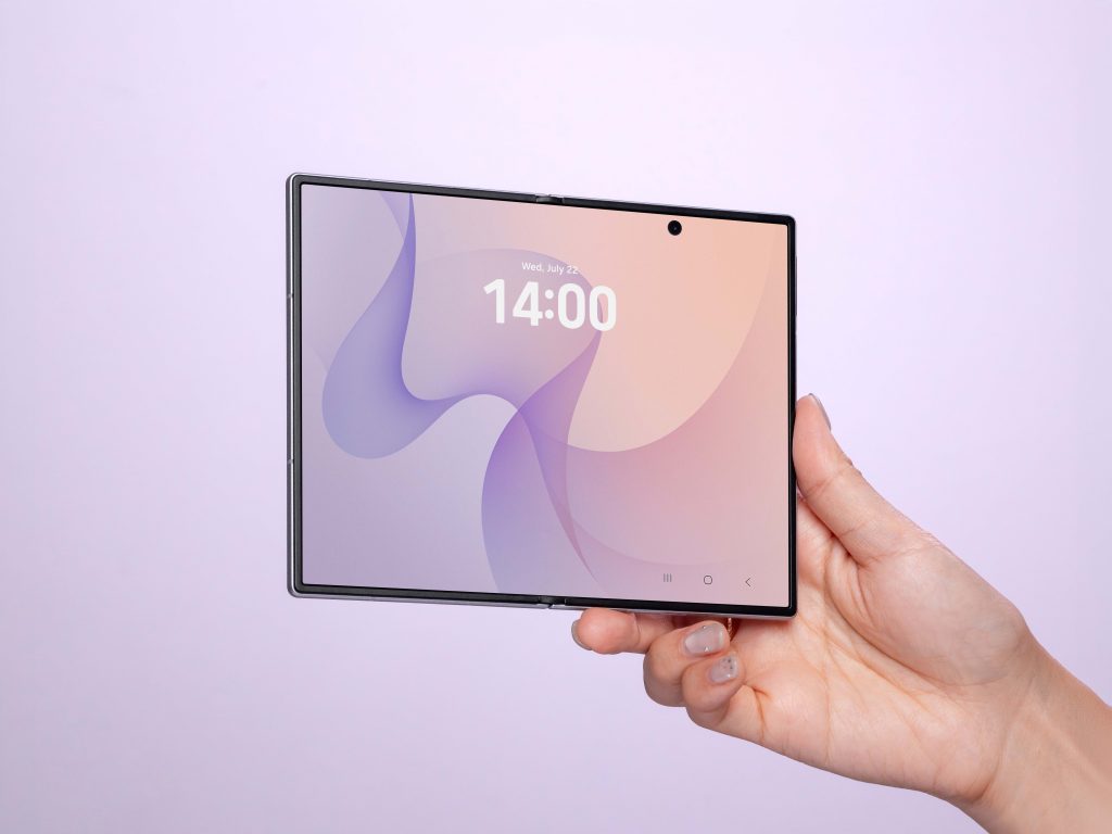 Mão segura o Galaxy Z Fold8 aberto, exibindo a tela principal de 7,6 polegadas com papel de parede em tons de lilás e rosa.
