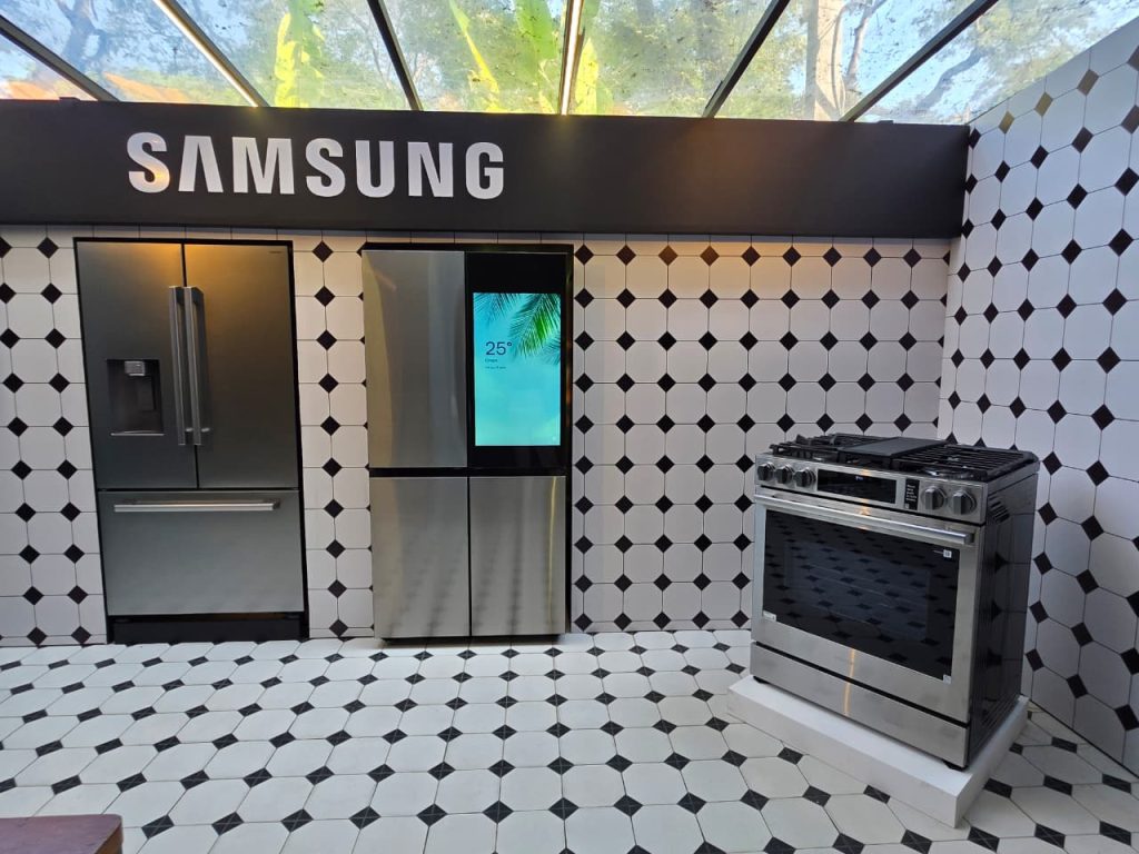 Espaço da Samsung no The Brief com geladeiras, incluindo modelo com tela, e fogão em ambiente com piso e paredes geométricos.