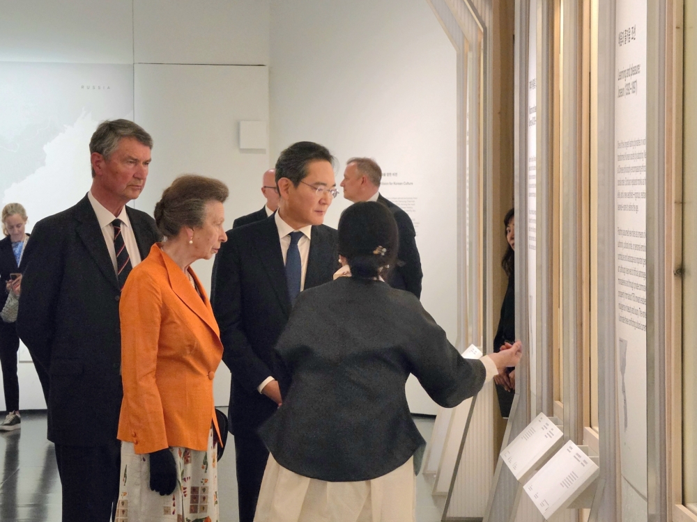 Mulher apresenta a um grupo de visitantes elemento de uma exposição no Museu Britânico