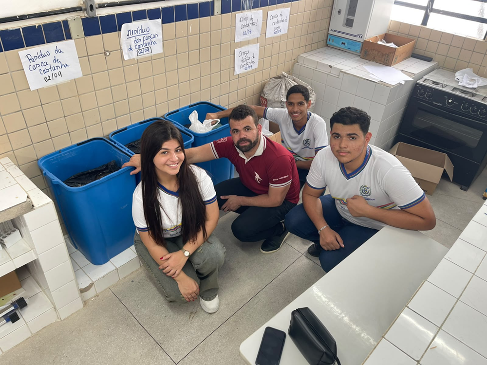 Dois alunos e uma aluna posam junto a professor em escola pública de Vertentes, em Pernambuco