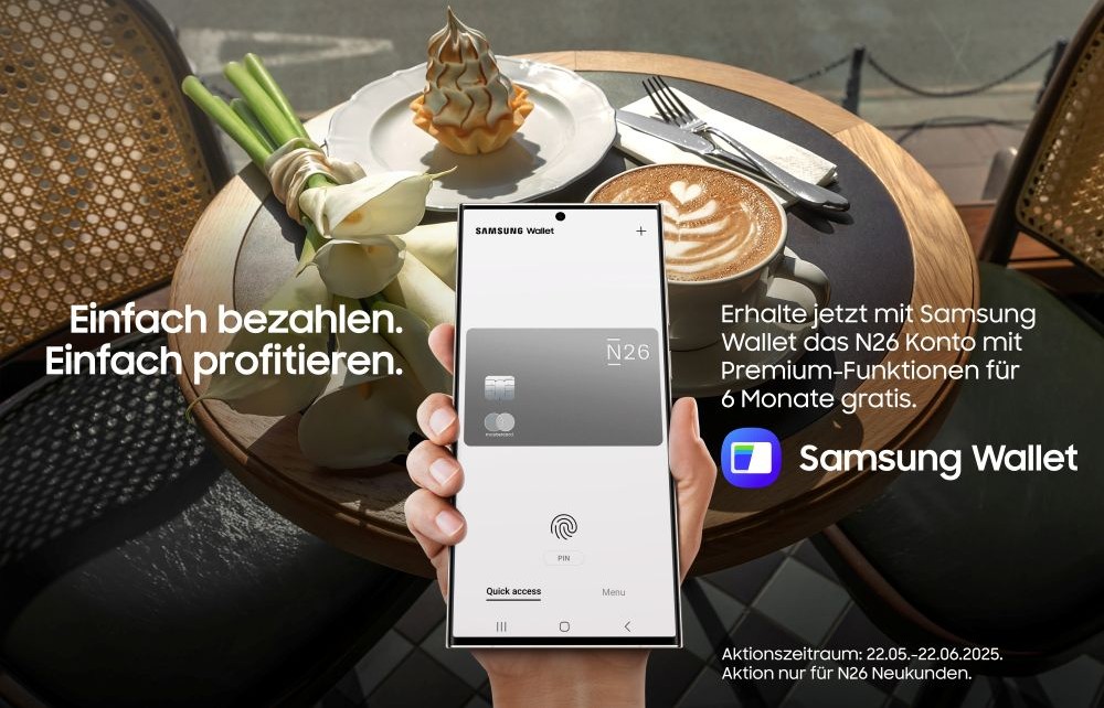 Smartphone mit N26 Kreditkarte auf dem Display, im Hintergrund ein gedeckter Tisch eines Cafés