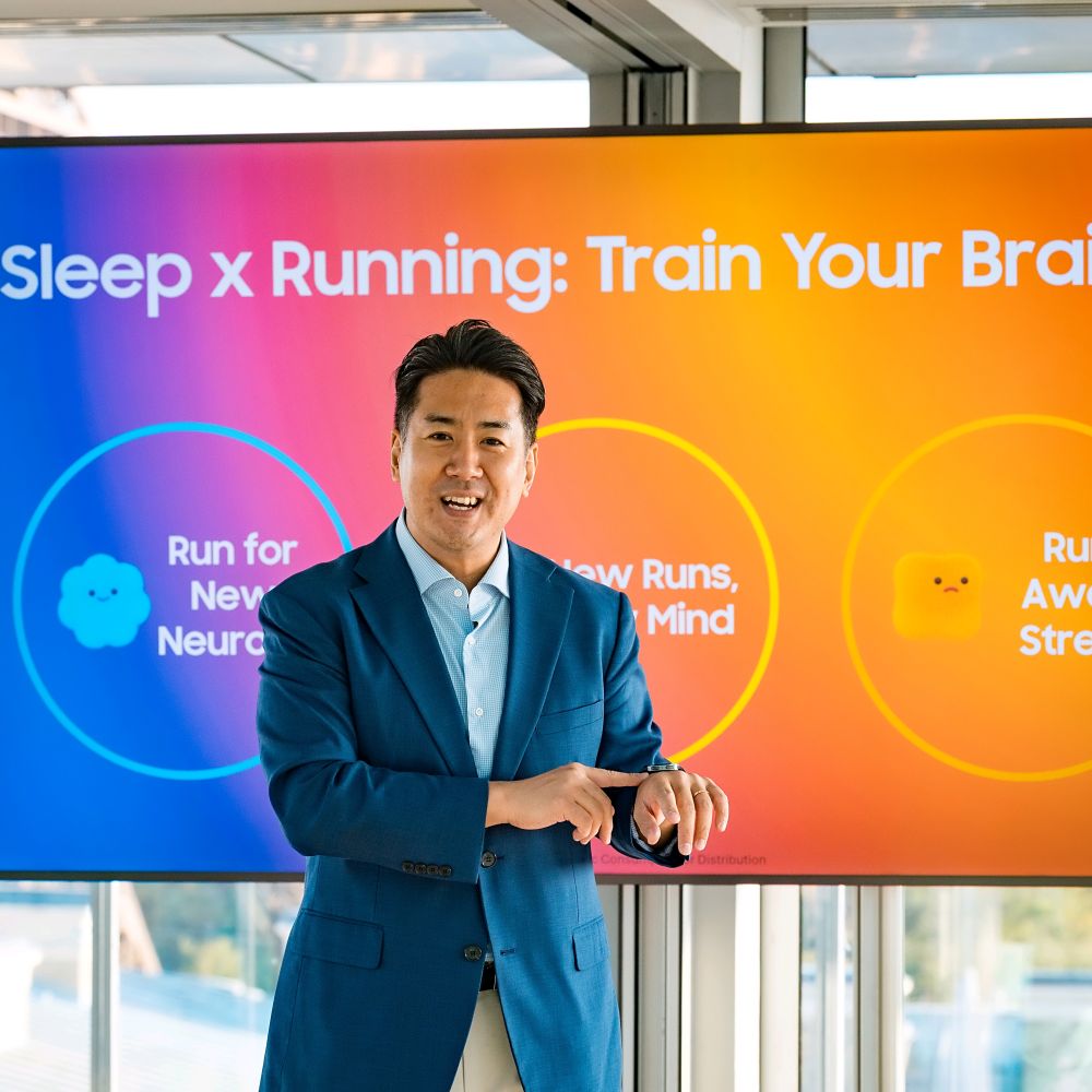 Referent im blauen Anzug spricht über das Thema Schlaf und Laufen, bunte Samsung-Präsentationsfolie im Hintergrund.