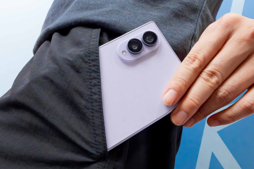 Nahaufnahme einer Hand, die ein geschlossenes Galaxy Z Fold8 an einer schwarzen Hosentasche hält. Auf der Rückseite ist die Kameraeinheit des Smartphones zu sehen.