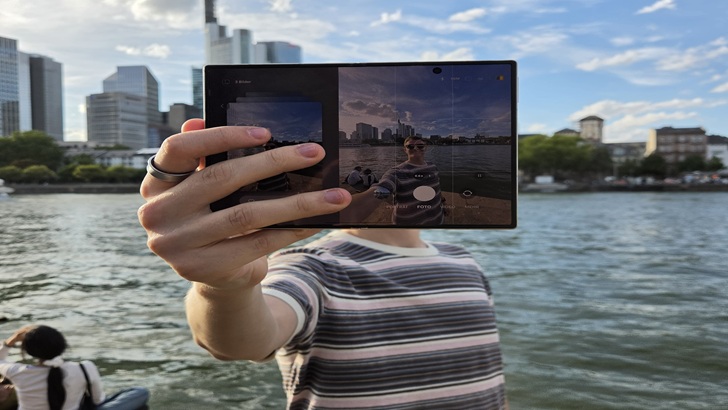 Eine Person hält ein aufgeklapptes Galaxy Z Fold8 vor die Frankfurter Skyline, um sich selbst zu fotografieren. Auf dem Display ist die Kameraansicht mit dem Motiv zu sehen. © Samsung Electronics