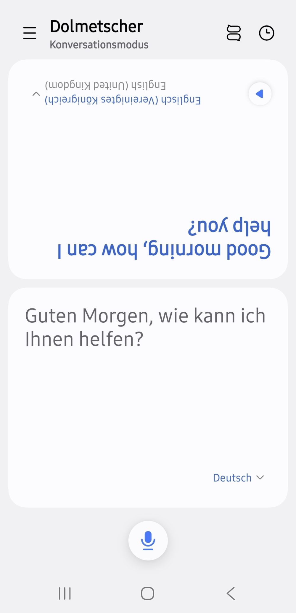 Screenshot der Dolmetscher-App eines Samsung Galaxy Smartphones im Konversationsmodus: Der Satz „Guten Morgen, wie kann ich Ihnen helfen?“ erscheint auf Deutsch in der unteren Bildschirmhälfte und um 180 Grad gedreht als englische Übersetzung „Good morning, how can I help you?“ in der oberen Hälfte.