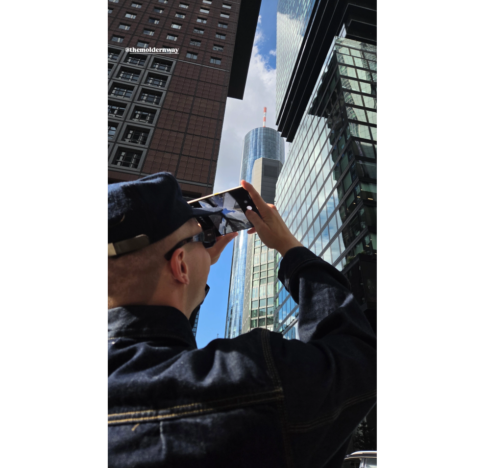 Der Fotograf Sascha Priesters hält ein Galaxy Z Fold8 vor einer Frankfurter Hochhauskulisse in die Kamera. © Samsung Electronics