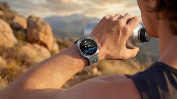 Läufer mit Samsung Galaxy Watch Ultra2 am Handgelenk hält während einer Laufeinheit in bergiger Landschaft eine Trinkflasche. Auf dem Display sind Trainingsdaten zu sehen. © Samsung Electronics