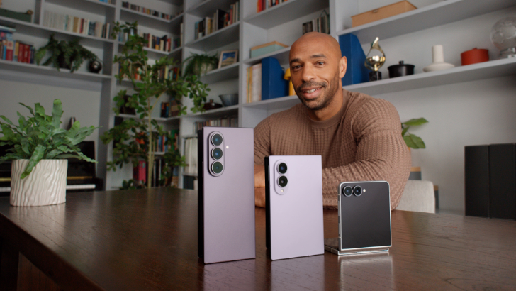 Der ehemalige Fußballstar Thierry Henry sitzt an einem Tisch vor einem Bücherregal. Vor ihm stehen die drei Geräte der Samsung Galaxy Z8-Serie.