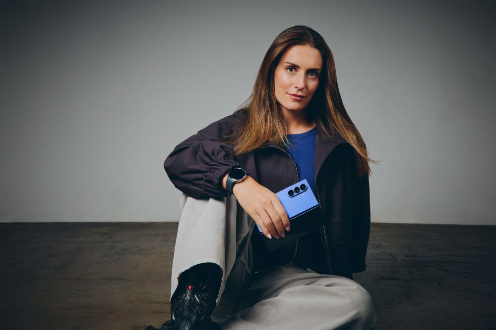 Alexia Putellas posa sentada con un smartphone plegable Samsung Galaxy azul y un Galaxy Watch, resaltando el diseño premium y la conectividad del ecosistema Galaxy.
