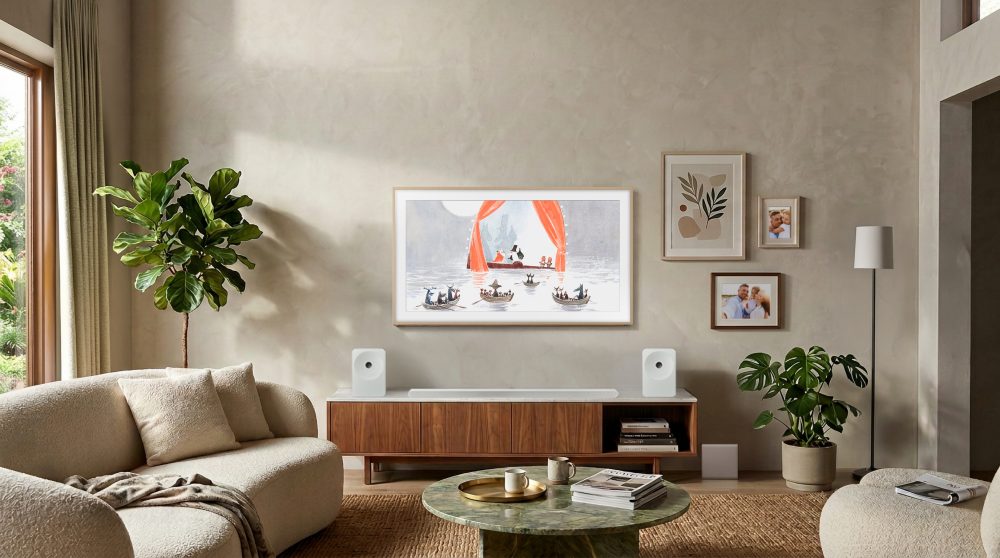 The Frame integrado en un salón contemporáneo, mostrando una obra de arte en pantalla y formando parte de una composición decorativa junto a cuadros, plantas y mobiliario de madera.