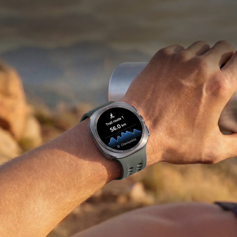 Samsung Galaxy Watch Ultra en la muñeca de un corredor de trail, mostrando en pantalla una ruta de 56 km con perfil de elevación durante una actividad al aire libre.