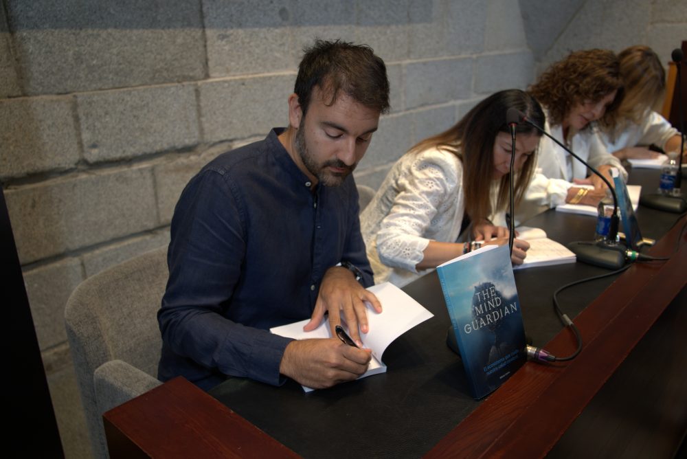 Varias personas firman ejemplares de The Mind Guardian: El ecosistema que cuida nuestra salud cerebral durante la presentación del libro.