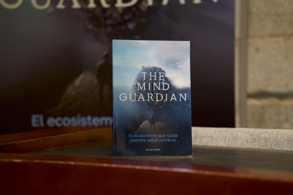 Libro The Mind Guardian: El ecosistema que cuida nuestra salud cerebral expuesto sobre una mesa durante un evento.