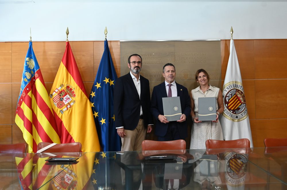 Representantes de la Universitat Politècnica de València posan tras la firma de un acuerdo, acompañados por las banderas de la Comunidad Valenciana, España, la Unión Europea y la UPV.
