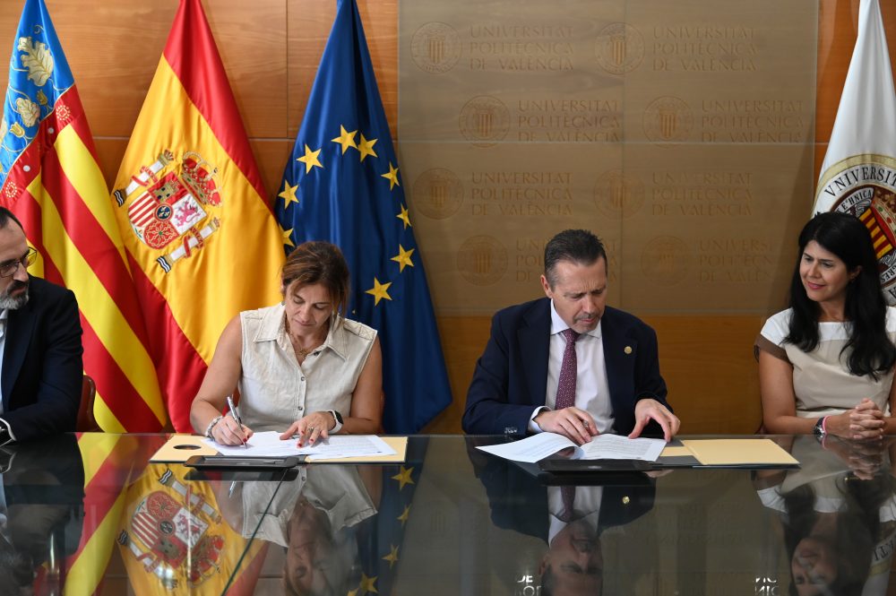 Representantes de la Universitat Politècnica de València durante la firma de un acuerdo, con las banderas de la Comunidad Valenciana, España, la Unión Europea y la UPV al fondo.
