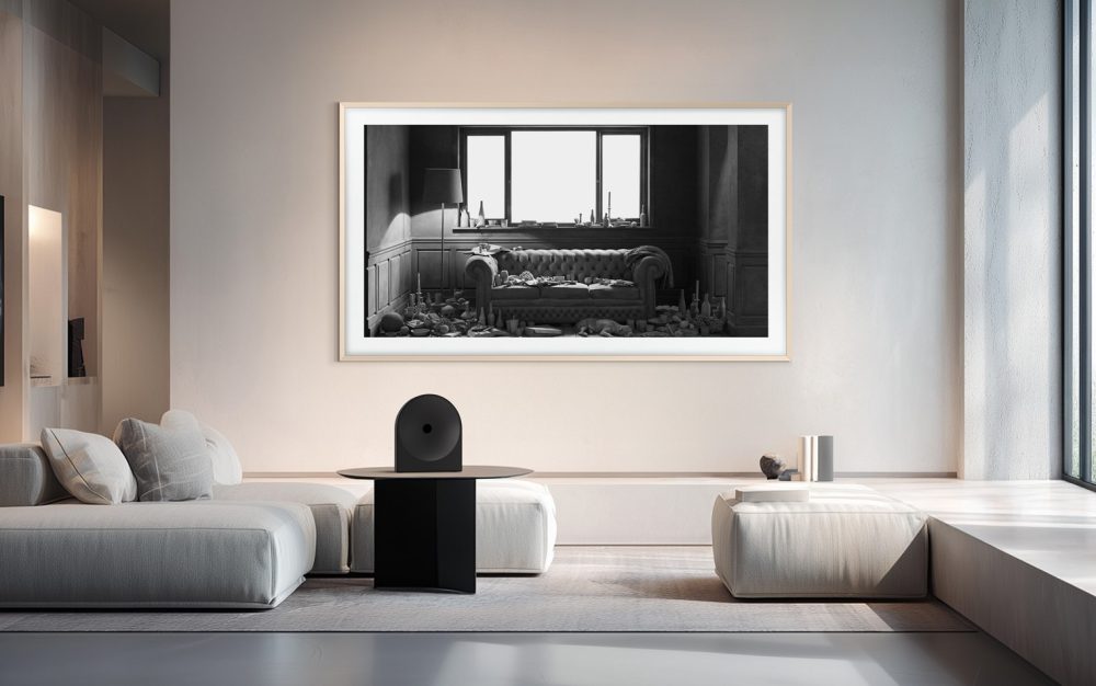 Samsung The Frame Pro instalado en la pared de un salón moderno y minimalista, mostrando una fotografía artística en blanco y negro, con sofá blanco y decoración contemporánea.