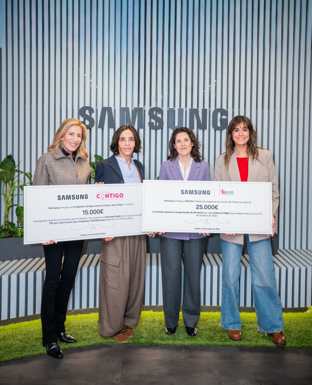 Cuatro representantes posan en las oficinas de Samsung con dos cheques solidarios de 150.000 euros para la Fundación Contigo y 25.000 euros para FECMA, destinados a apoyar la lucha contra el cáncer de mama.