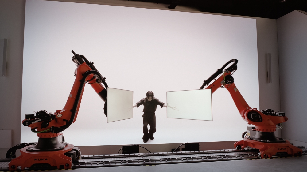 The KUKA robots perform in harmony with the dancer displayed on the large Samsung LED signage (IEA series) behind them.