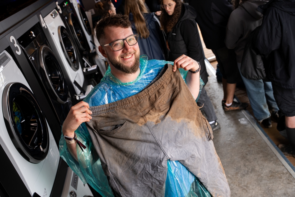 A festival-goer shows off his muddy trousers before loading them into a washer at Samsung Electronic's WashPoint.