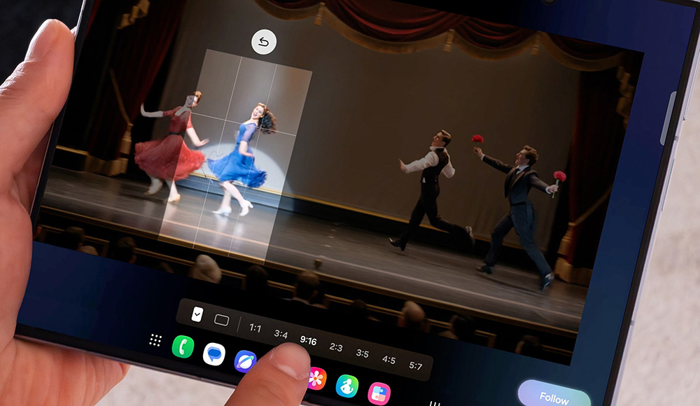 A person's hand holding a tablet with a screen showing a group of people dancing