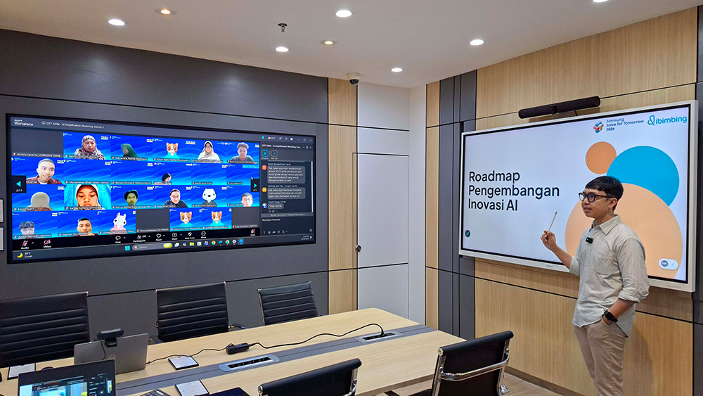 Mentor memaparkan materi Roadmap Pengembangan Inovasi AI di depan layar presentasi, sementara peserta Samsung Solve for Tomorrow 2026 mengikuti secara online melalui layar video conference di kantor Samsung Indonesia.