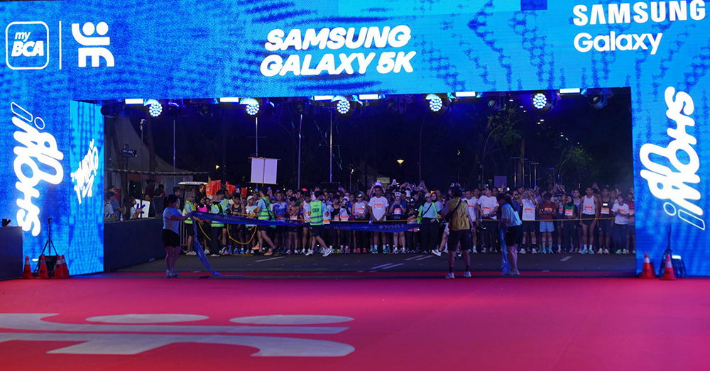 Pelari bersiap di bawah gerbang start Samsung Galaxy 5K yang menyala biru sebelum fajar di Jakarta Running Festival 2026