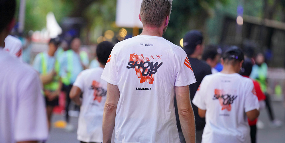 Sejumlah pelari tampak dari belakang mengenakan jersey putih bertuliskan Show Up dan logo Samsung di Jakarta Running Festival 2026