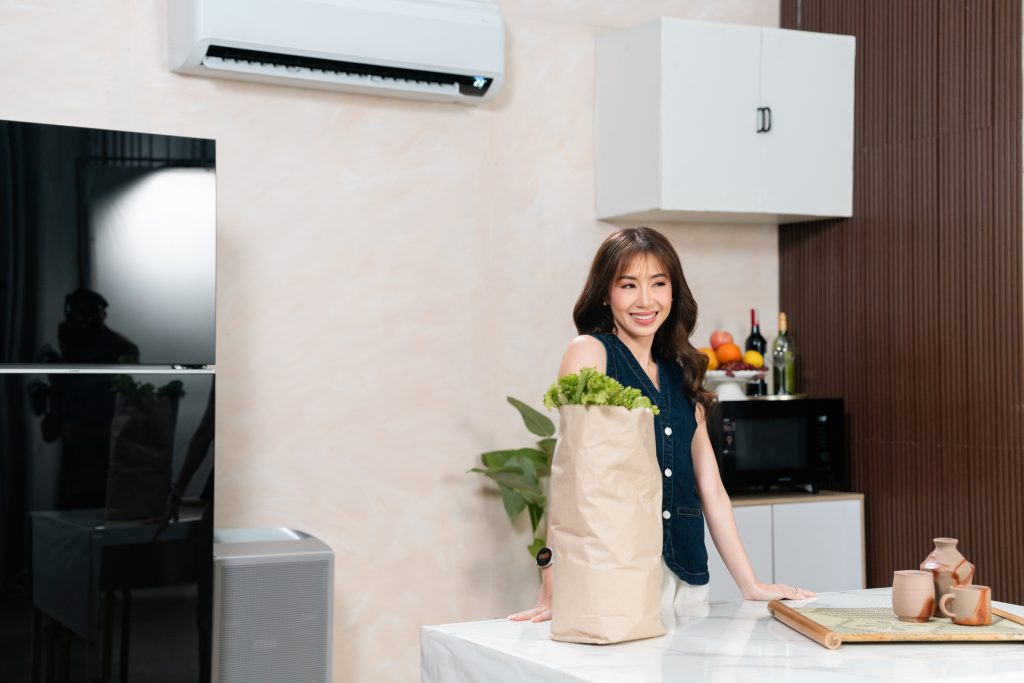 Kryz Uy standing in her kitchen being cooled by Samsung AI WindFree™